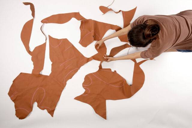 Mimansa from RCA laying out brown leather material offcuts for her project.
